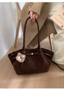 Detail of dark brown fuzzy tote bag featuring leather handles and cute bear charm
