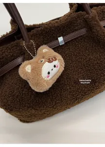 Detail of plush brown shearling tote bag featuring a cute removable bear pendant