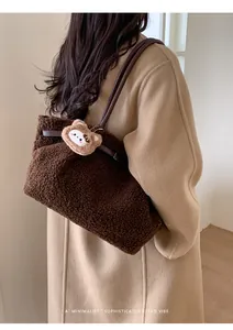 Detail view of large faux fur tote bag with brown leather straps and bear charm