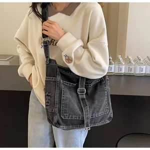 Detail of dark gray denim messenger bag showing functional pockets and adjustable wide strap