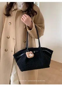 Close-up of black fuzzy lamb wool shoulder bag with brown plush bear charm accessory