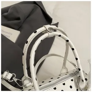 Detalle de las asas del bolso de lunares blancos con hebilla metálica y cremallera