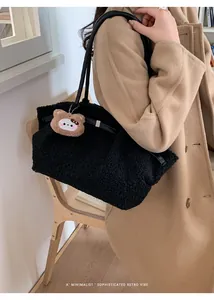 Detail of black fuzzy tote bag with leather strap, metal buckle and a cute bear charm