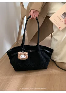 Detail of black fuzzy tote bag with bear charm and leather strap in lifestyle setting