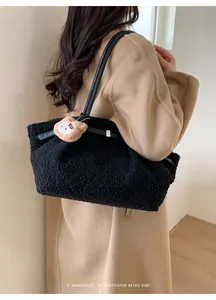 Detail of black faux shearling tote bag with leather straps and a brown plush bear charm