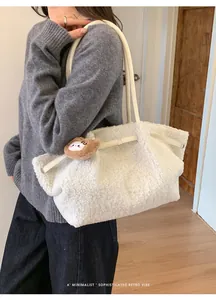 Detail of off-white fuzzy tote bag with soft teddy texture and brown bear charm accessory