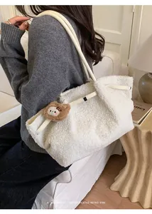 Detail view of cream plush tote bag texture with brown teddy bear charm accessory