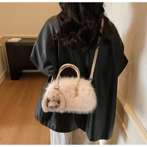Detail of plush faux fur handbag in soft pink with leather handles and bunny charm