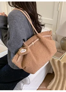 Brown fuzzy tote bag with leather straps and bear charm shown in a cozy indoor setting