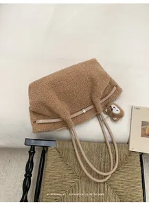 Detail of plush tote bag with brown sherpa texture and leather straps and bear charm
