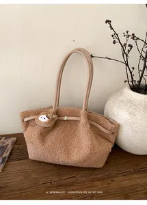 Detail of plush brown shearling tote bag with leather handles and cute bear charm