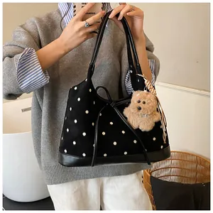 Close-up of vintage black polka dot tote bag with leather bow and plush bear charm