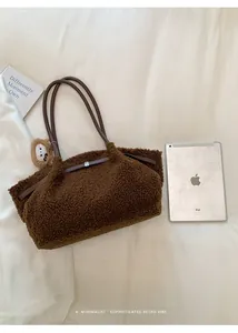Detail view of large brown fuzzy fleece tote bag with leather straps and bear charm