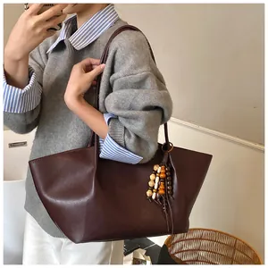 Detail of dark burgundy oil wax leather tote bag with colorful beaded tassel charm