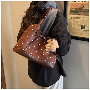 Detail of vintage brown polka dot tote bag with leather bow and plush bear charm