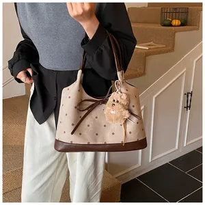 Detail of vintage polka dot tote bag with brown leather accents and plush puppy pendant