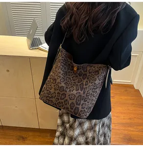 Detail van luipaardprint suède bucket bag met gouden sluiting over de schouder