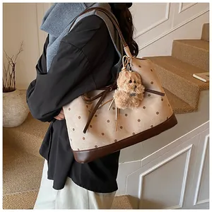 Detailed view of large polka dot tote bag with brown leather trim and plush puppy charm