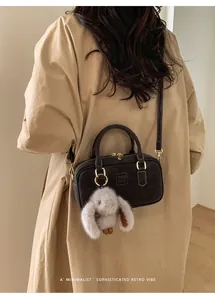 Detail of dark brown retro pillow bag with golden zippers and a cute rabbit charm