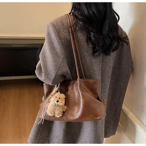 Detail van vintage bruine leren tas met een schattige pluche puppy tashanger