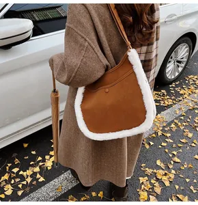 Detailed view of brown suede bucket bag with white faux fur trim in an autumn outdoor setting