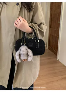 Detail of black retro pillow bag with golden hardware and a cute plush bunny pendant