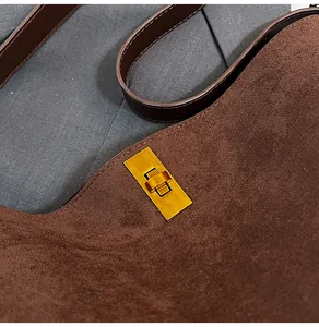 Close-up of the vintage gold twist lock on a dark brown suede bucket tote bag