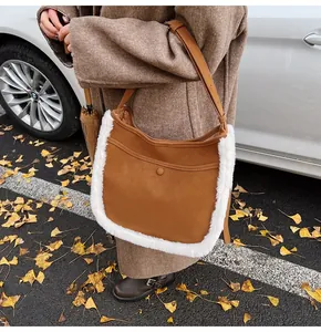 Detail of suede bucket bag with white faux fur trim and front snap pocket for women