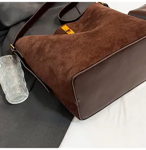 Detail of dark brown suede tote bag with metallic gold twist lock and leather textures