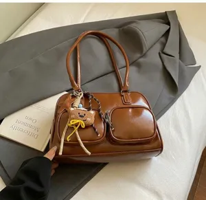Dettaglio borsa tote in pelle marrone vintage con tasche e ciondolo a forma di orso