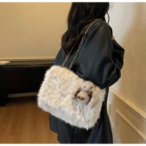 Detail of white faux fur shoulder bag with gold chain strap and cute rabbit pendant