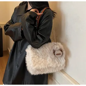 Detail einer Plüsch-Schultertasche mit goldener Kette und Hasen-Anhänger für Damen