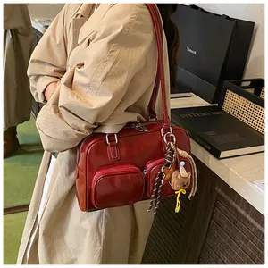 Dettaglio borsa a spalla bordeaux lucida con tasche con zip e ciondolo a forma di orso