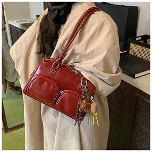 Dettaglio borsa a spalla rossa lucida con doppie tasche a zip e pendente a stella
