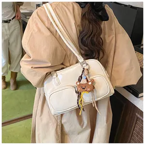 Dettaglio borsa a spalla in ecopelle beige con doppie tasche e ciondolo a forma di orso