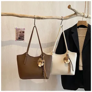 Detail of brown and cream tote bags with bear charms on a wooden branch hanger
