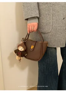 Detail der braunen Wildleder-Tragetasche mit Teddybär-Anhänger und strukturierter Oberfläche