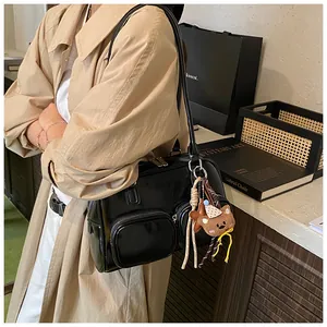 Dettaglio borsa a tracolla Boston nera con tasche a cerniera e ciondolo a forma di orso