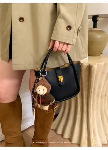 Detail der schwarzen Lederbeuteltasche mit Goldschloss und süßem Bärenanhänger