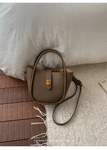 Detailansicht der dunkelbraunen Ledertasche mit goldener Schnalle auf weißem Teppich
