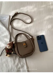 Flache Ansicht einer dunkelbraunen Leder-Tote-Bag mit Bärenanhänger und Goldschnalle