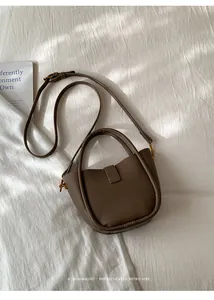 Detailansicht der kaffeebraunen Beuteltasche aus Leder mit Litschi-Muster und Goldakzenten