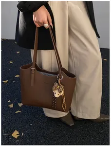 Detail of dark brown pebble leather tote bag with MOCOHU logo and bear charm