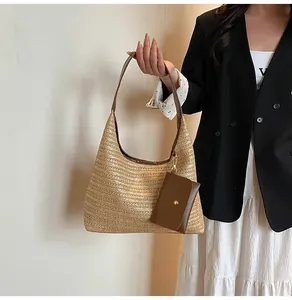 Detail of light brown straw tote bag with brown leather handles and matching pouch accessory
