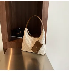 Detail of a beige woven tote bag with brown leather handles and a matching mini pouch