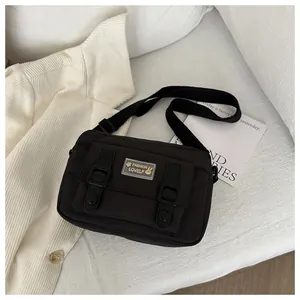 Detailopname van zwarte nylon crossbodytas met gespsluiting en merklogo op de voorkant