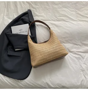 Detail of light beige straw woven hobo bag with contrast dark brown faux leather trim