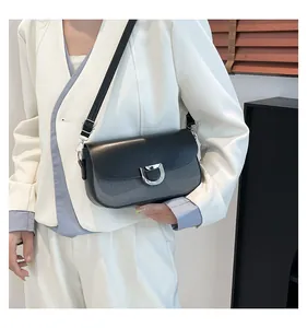 Dettaglio della borsa a tracolla con texture in pelle e fibbia a ferro di cavallo