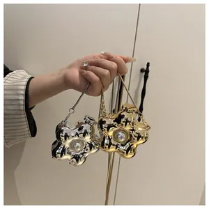 Detail of flower shaped mini metal bag with center pearl and delicate chain strap