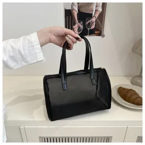 Detail of black mesh cylinder handbag with dual handles and top zipper closure